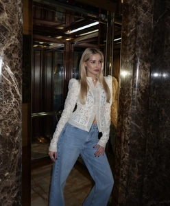 Detalle de la blusa de encaje blanco combinada con vaqueros azules de pernera ancha y talle alto