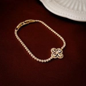 Detailed macro shot of a gold tennis bracelet featuring a sparkling clover pendant and clasp