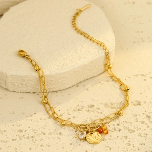 Detail of gold double-layer bracelet with waterdrop zircon and sunface coin pendant