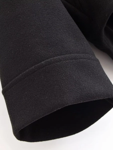Detailed close-up of heavy wool fabric texture and double-stitch sewing on the black cuff