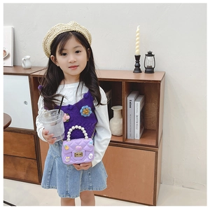 Girl modeling a purple quilted cross-body bag with pearl handle and metal chain strap
