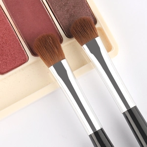 Close-up of dual-ended eyeshadow brushes with soft brown bristles and wood handles
