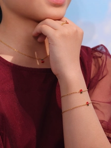 Bambina che indossa un set di collana, bracciale e anello a fragola in acciaio dorato