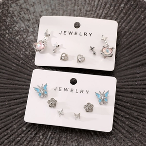 Detail of multi-piece alloy earring set featuring blue butterflies and pink star shapes