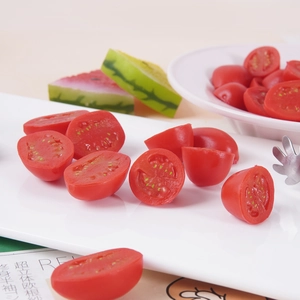 Realistic artificial cherry tomato model with detailed red pulp texture in a white tray