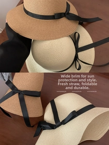 Close-up of foldable woven straw hat with black ribbon bow and wide brim design