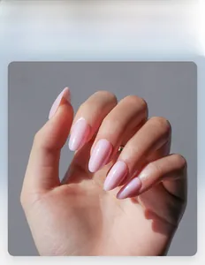Dettaglio macro di unghie finte rosa perlato a mandorla con sottile effetto glitterato
