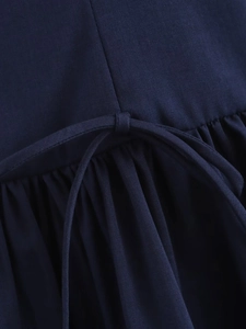 Detail of dark blue dress featuring waist tie-up bow and elegant pleated fabric texture