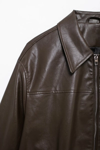Detailed macro view of the dark brown faux leather texture and silver zipper of the jacket
