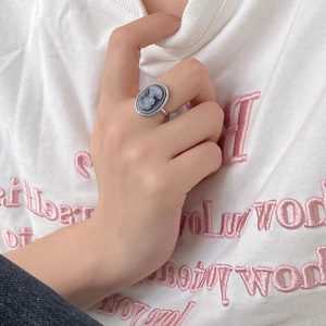 Silver vintage cameo ring with oval portrait relief worn on a hand against a white tee