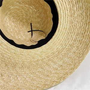 Detail of straw sun hat interior featuring black sweatband and adjustable drawstring