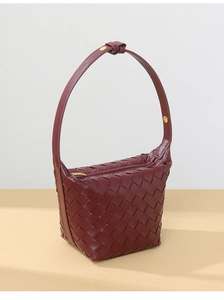 Detail of burgundy woven texture and golden buckle on soft leather shoulder bag