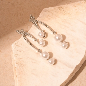 Detail of silver drop earrings with crossover crystals and cascading white pearls