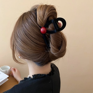 Detail of red bead velvet hair claw clip on elegant updo hairstyle back view