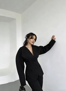 Détail d'un ensemble tailleur noir avec blazer à manches bouffantes et décolleté en V chic