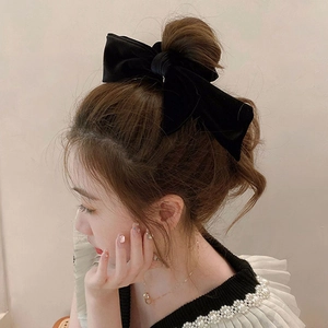 Detailed view of a premium black velvet oversized bow hair tie worn on a model's hair