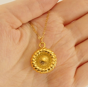 Macro shot of a gold-plated stainless steel sunburst pendant with a twisted rope border design