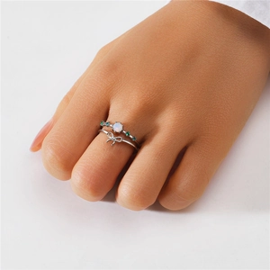 Detail of stacked S925 silver rings with butterfly charm and opal with colorful stones