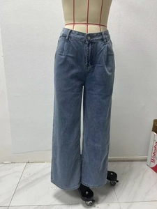 Close-up of high-waisted wide-leg denim jeans with pleated details and washed finish