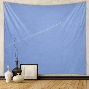 Detail of light blue bohemian tapestry with minimalist airplane trail on a wall
