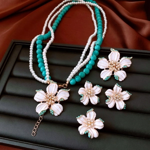 Macro view of vintage style flower necklace with pearls and turquoise beads on tray