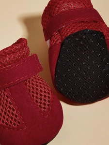 Close-up of red breathable mesh dog shoes with non-slip rubber soles and velcro straps