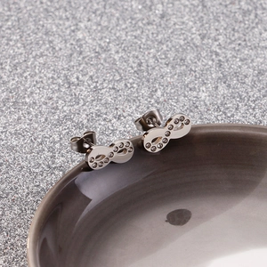 Macro shot of silver infinity symbol stud earrings with zircons on ceramic bowl