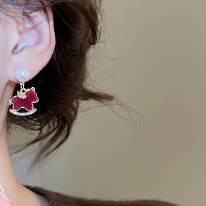 Detail of red rocking horse earring with pearls and diamonds on woman's ear