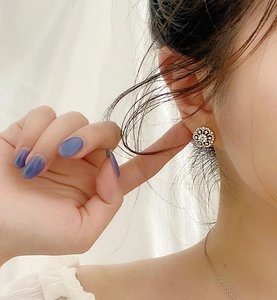 Macro detail of 925 silver floral stud earring with crystals worn by a model
