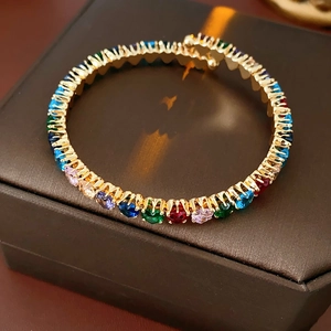 Close-up of gold bangle with multi-colored circular zircons in prong setting