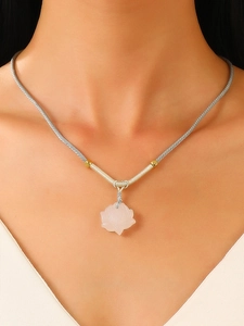 Close-up of a pink lotus flower pendant with a silver-grey woven cord on a model