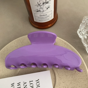 Macro detail of a large purple glossy acetate hair claw clip on a ceramic tray
