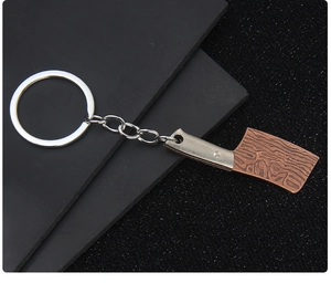 Detail eines Mini-Hackmesser-Schlüsselanhängers mit Kupferklinge und Silbergriff auf dunklem Grund