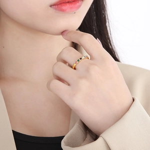 Detail of gold stackable ring set with vibrant colorful cubic zirconia on model's hand