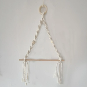 Detail of bohemian hand-woven cotton rope towel holder with wooden ring and beads