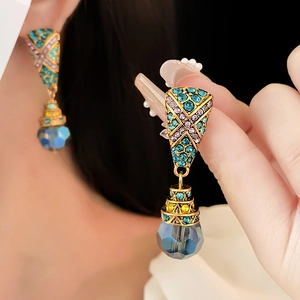 Detail of vintage gold earrings with blue water-drop crystals and colorful rhinestones