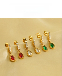 Detail view of teardrop zircon earrings with pearls on champagne silk fabric background