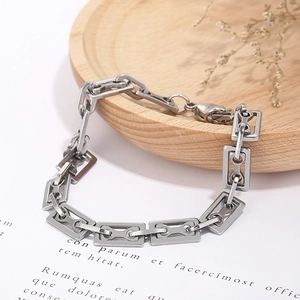 Detailed macro shot of a geometric rectangular silver steel bracelet on a wood tray