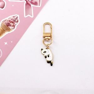Close-up of cute alloy cat keychain with golden lobster clasp and white spotted cat charm