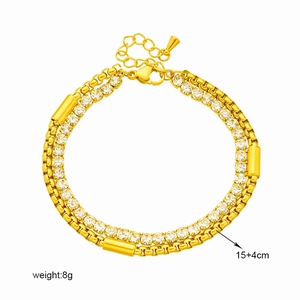 Golden double-layer chain bracelet with zircon accents and cylindrical charms on white background