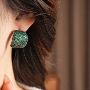 Gros plan de boucles d'oreilles vintage avec zircons verts portées par un mannequin