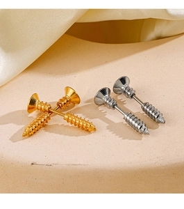 Macro shot of gold and silver screw-shaped stud earrings on a beige textured base