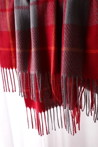 Macro detail of red and grey checkered scarf with thick fringe edges and soft texture