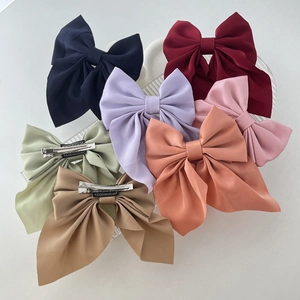 Colorful set of satin bow hair clips in assorted shades on a wavy transparent tray