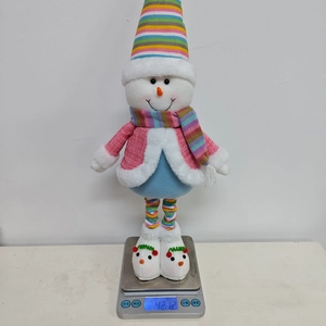Pink plush Christmas snowman doll being weighed on a digital scale showing 421.2g