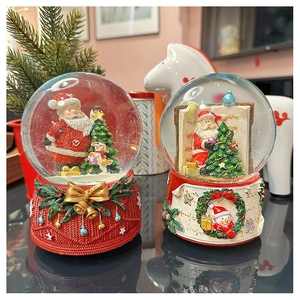 Close-up of festive Christmas snow globes with Santa Claus and reindeer on resin bases