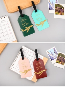 Flat lay of colorful faux leather airplane luggage tags with gold TRAVEL SWING TAG text