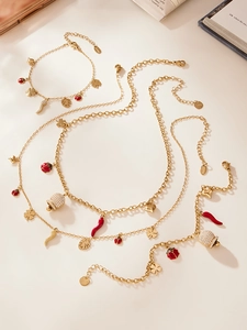 Vue à plat de bijoux dorés avec pendentifs coccinelle, trèfle et cloche en cristal