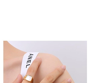 Close-up of a gold ring with a white square stone worn on the finger in minimalist style