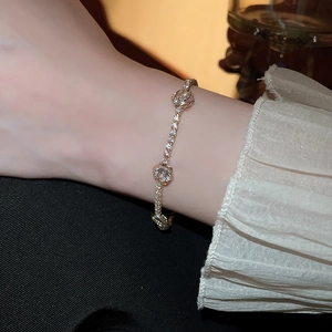 Macro detail of a gold flower bracelet with zircon stones and elegant lace sleeve